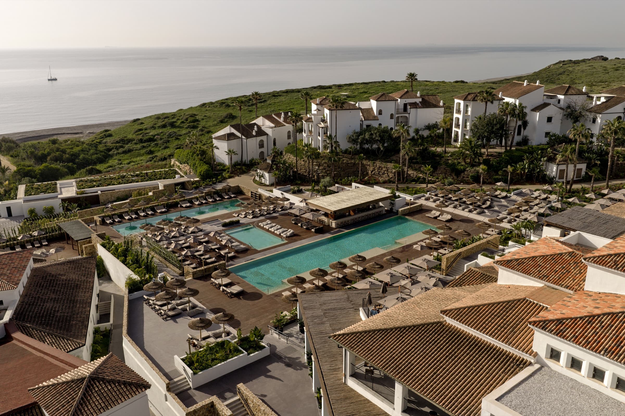 Aerial view of OKU Andalusia: the main pool, white-washed village and the Mediterranean beyond.